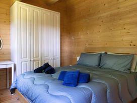 A bedroom with a bed and wardrobe at Owl Lodge in Menheniot