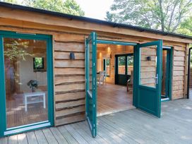 An outdoor view of a wooden cabin with open doors at Owl Lodge Menheniot