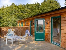 A deck area with chairs and a table at Owl Lodge in Menheniot