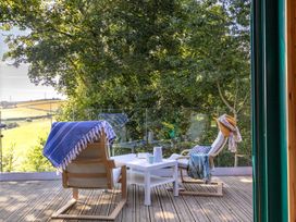 An outdoor sitting area with chairs and a table at Owl Lodge in Menheniot
