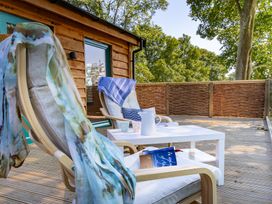 A deck with chairs, table, and a book at Owl Lodge in Menheniot