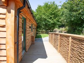An outdoor view of a wooden cabin and deck at Owl Lodge in Menheniot