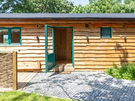 An outdoor view of a wooden lodge with a gravel pathway at Owl Lodge Menheniot