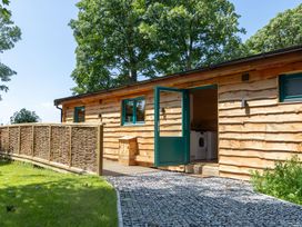 A wooden cabin with an open door and a washing machine visible at Owl Lodge Menheniot