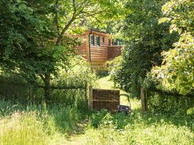 A garden with a wooden building and gate at Owl Lodge in Menheniot