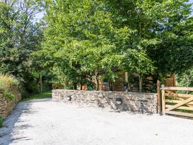 An outdoor path with trees and a stone wall at Owl Lodge Menheniot