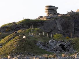 A rocky landscape with a sheep and a person at Owl Lodge in Menheniot