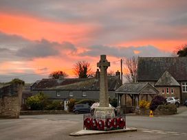 A Celtic cross with wreaths in front of buildings at Owl Lodge Menheniot