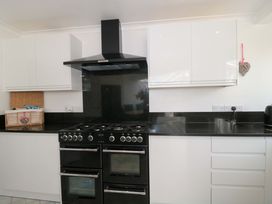 A kitchen with a black oven and white cabinets at No 8 Burnham-on-Sea