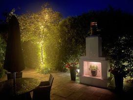A garden with a table, umbrella, and a fireplace with a plant at No 8, Burnham-On-Sea