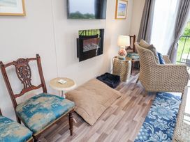 A sitting area with antique wooden chairs a woven armchair small side tables lamps a wall mounted tv and fireplace and pet beds at The Hoot in Great Finborough near Stowmarket