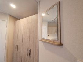 A hallway with wooden wardrobes and a wall-mounted mirror at The Hoot in Great Finborough near Stowmarket