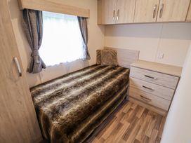 A bedroom with a bed covered in a fur blanket next to a window and a chest of drawers at The Hoot in Great Finborough near Stowmarket