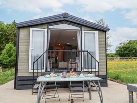 An outdoor dining table with chairs set in front of a small house with open double doors at The Hoot in Great Finborough near Stowmarket