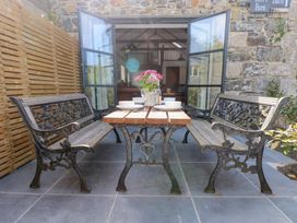 An outdoor seating area with benches and a table at Joe's Barn in Mullion