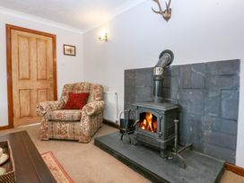 A living room with a fireplace and armchair at Tir Mawr in Llanfairpwllgwyngyll