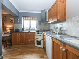 A kitchen with cabinets, oven, sink, and a dishwasher at Tir Mawr in Llanfairpwllgwyngyll