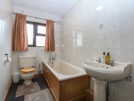 A bathroom with a bathtub, toilet, and washbasin at Tir Mawr in Llanfairpwllgwyngyll