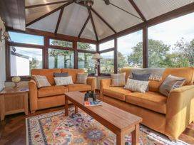 A conservatory with two couches and a coffee table at Tir Mawr in Llanfairpwllgwyngyll