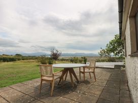 A patio with a table and chairs overlooking mountains at Tir Mawr in Llanfairpwllgwyngyll