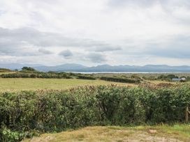 A view of a field with a hedge and mountains at Tir Mawr in Llanfairpwllgwyngyll