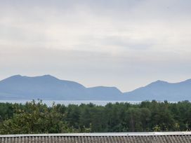A view of mountains and a lake with trees in the foreground at Tir Mawr in Llanfairpwllgwyngyll