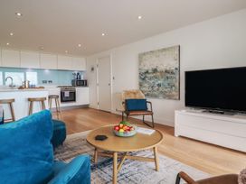 A living room with a sofa, coffee table, and kitchen area at 4 Ocean Gate in Newquay