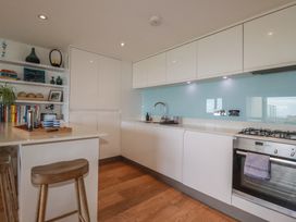 A kitchen with cabinets, stove, sink, and bar stools at 4 Ocean Gate in Newquay