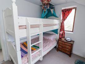 A bunk bed with a nightstand and lamp in a bedroom at Pencestyll in Cardigan