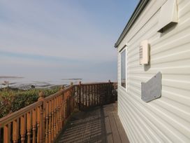 A wooden deck with railing outside a mobile home overlooking a coastal landscape at Bayview 23 in West Quantoxhead