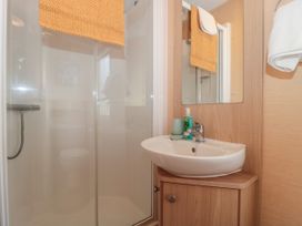 A bathroom with a shower cubicle a sink a mirror and towels at Bayview 23 in West Quantoxhead