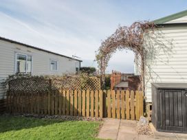 A fenced outdoor area with two mobile homes and a wooden archway at Bayview 23 in West Quantoxhead
