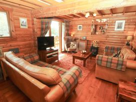A living room with a sofa and television at Thistle Dubh ('Doo') Sandyhills