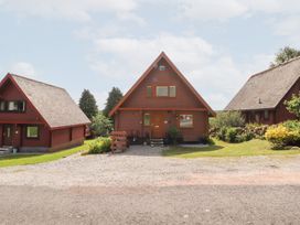 A log cabin with a front door and garden at Thistle Dubh ('Doo') in Sandyhills