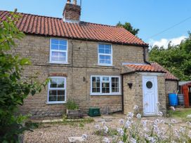 A stone house with a red tiled roof three windows a white door and plants in the front at 2 Beck Houses Menethorpe near Malton