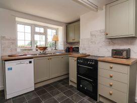 A kitchen with grey cabinets a dishwasher a black oven a toaster and a window at 2 Beck Houses Menethorpe near Malton