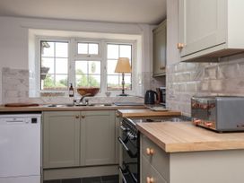 A kitchen with cabinets dishwasher stove toaster and window at 2 Beck Houses Menethorpe near Malton
