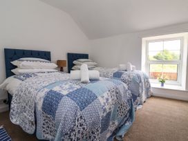 A bedroom with two single beds covered with blue and white quilts and rolled towels on each bed at 2 Beck Houses in Menethorpe near Malton