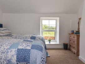 A bedroom with twin beds near a window and a wooden dresser at 2 Beck Houses in Menethorpe near Malton