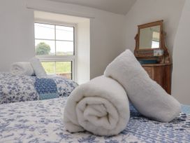 A bedroom with rolled white towels on blue and white floral bedding and a wooden dresser with a mirror at 2 Beck Houses Menethorpe near Malton