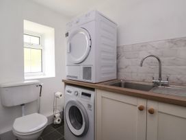 A utility room with a toilet washing machine dryer and sink at 2 Beck Houses Menethorpe near Malton