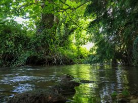 A flowing stream surrounded by trees and dense greenery at 2 Beck Houses in Menethorpe near Malton