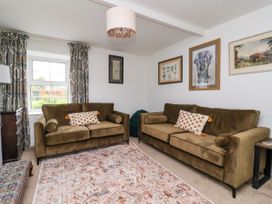 A sitting room with two olive green sofas and framed pictures on the walls at 2 Beck Houses in Menethorpe near Malton