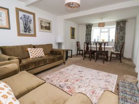 A living room with brown sofas a patterned rug a dining table with chairs and framed artwork at 2 Beck Houses in Menethorpe near Malton