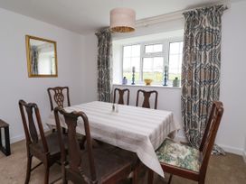 A dining room with six wooden chairs around a table with a striped tablecloth and patterned curtains at 2 Beck Houses Menethorpe near Malton