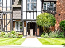 The front entrance of a Tudor style house with a pathway, trimmed lawn and a shaped tree at Tudor Grange in Bournemouth