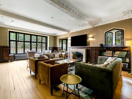 A living room with sofas armchairs a coffee table fireplace and large windows at Tudor Grange in Bournemouth