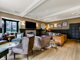 A sitting room with multiple armchairs and sofas around small tables at Tudor Grange in Bournemouth
