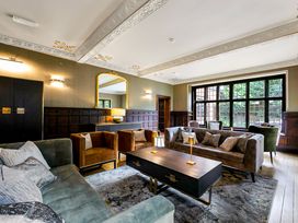A living room with sofas armchairs a coffee table and a large window at Tudor Grange in Bournemouth