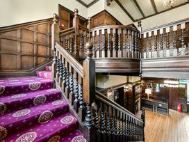 A wooden staircase with patterned carpet and wood panel walls at Tudor Grange in Bournemouth